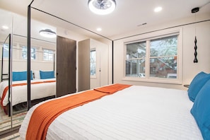 A bedroom with a large bed, a window, and a mirror.