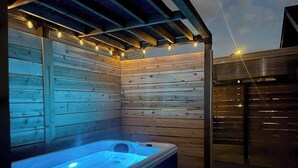 Un bain à remous dans un chalet en bois, illuminé de guirlandes lumineuses.