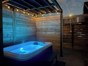 A hot tub in a wooden cabin with string lights.