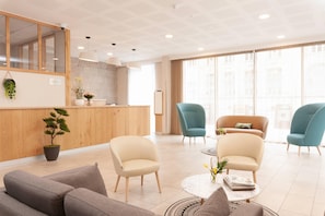 A modern hotel lobby with a reception desk, seating area, and large windows. - Quality Aparthotel Pau Porte des Pyrénées (Pau)