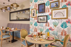 A dining area with a round table set for breakfast, featuring plates of food, drinks, and a variety of tableware. - Quality Aparthotel Pau Porte des Pyrénées (Pau)