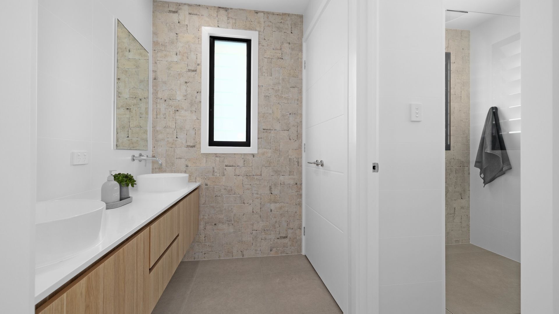 A modern bathroom with a stone wall, a large mirror, and a white vanity.