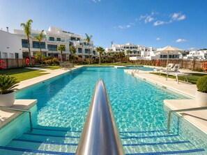 A clear swimming pool with steps leading into it, surrounded by lounge chairs and palm trees. - Casa Banderas Atico de lujo 4BR piscina privada (Mijas)