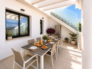 Un comedor con una mesa dispuesta para cuatro personas, un refrigerador y plantas en macetas.