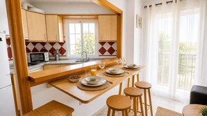 A kitchen with wooden cabinets, a microwave, a sink, and a dining area with stools and a table set for a meal. - Marbella Old Town - pedestrian area - walk to beach (Marbella)