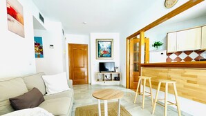 A living room with a sofa, a coffee table, and a TV. There is a wooden door leading to another room. - Marbella Old Town - pedestrian area - walk to beach (Marbella)