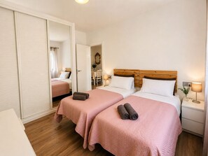Une chambre d’hôtel avec deux lits, une tête de lit en bois, des lampes de chevet et un miroir.