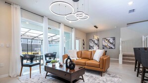 A modern living room with a brown leather sofa, a coffee table, and a dining area with a table and chairs.