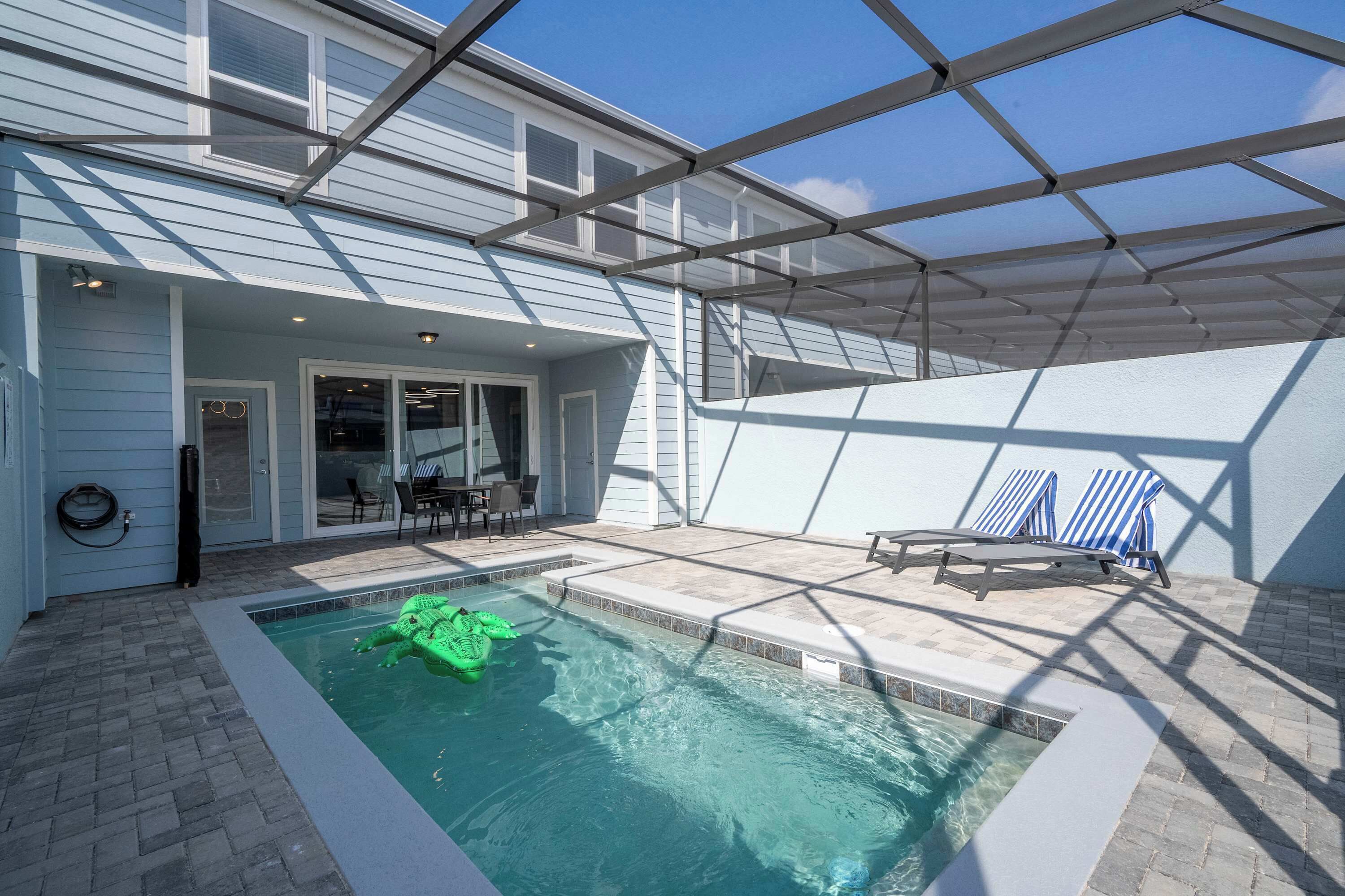A backyard with a swimming pool, a covered patio area, and a dining area with outdoor furniture.