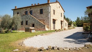 A stone building with a gravel driveway and a clear sky. - Corbezzolo (Asciano)
