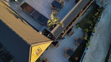 Vista aérea de una terraza en la azotea con mobiliario exterior y una pequeña área ajardinada.