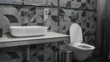 A modern bathroom with a geometric tile backsplash, a white sink, a toilet, and a shower curtain.