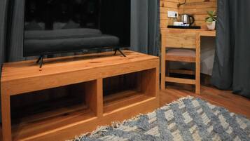 Un mueble de madera con un centro de entretenimiento, un televisor de pantalla plana, una pequeña mesa de madera con una tetera y una silla.