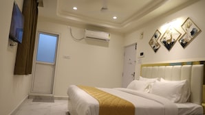 A hotel room with a bed, a TV, an air conditioning unit, and a door. - THE NECTAR HOTEL  (Hyderabad)