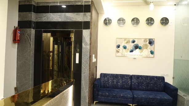 A reception area with a marble reception desk, a blue sofa, and a wall clock. - THE NECTAR HOTEL  (Hyderabad)