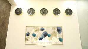 Five wall clocks and a floral art piece on a wall. - THE NECTAR HOTEL  (Hyderabad)