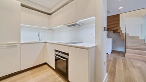 A modern kitchen with white cabinetry, a built-in oven, and a stainless steel sink. - Luxury 2 Bedroom Hyde Park Penthouse with Rooftop (London)