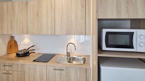 A kitchen with wooden cabinets, a stainless steel sink, a microwave, and a cutting board. - Quality Aparthotel Nancy Centre (Nancy)