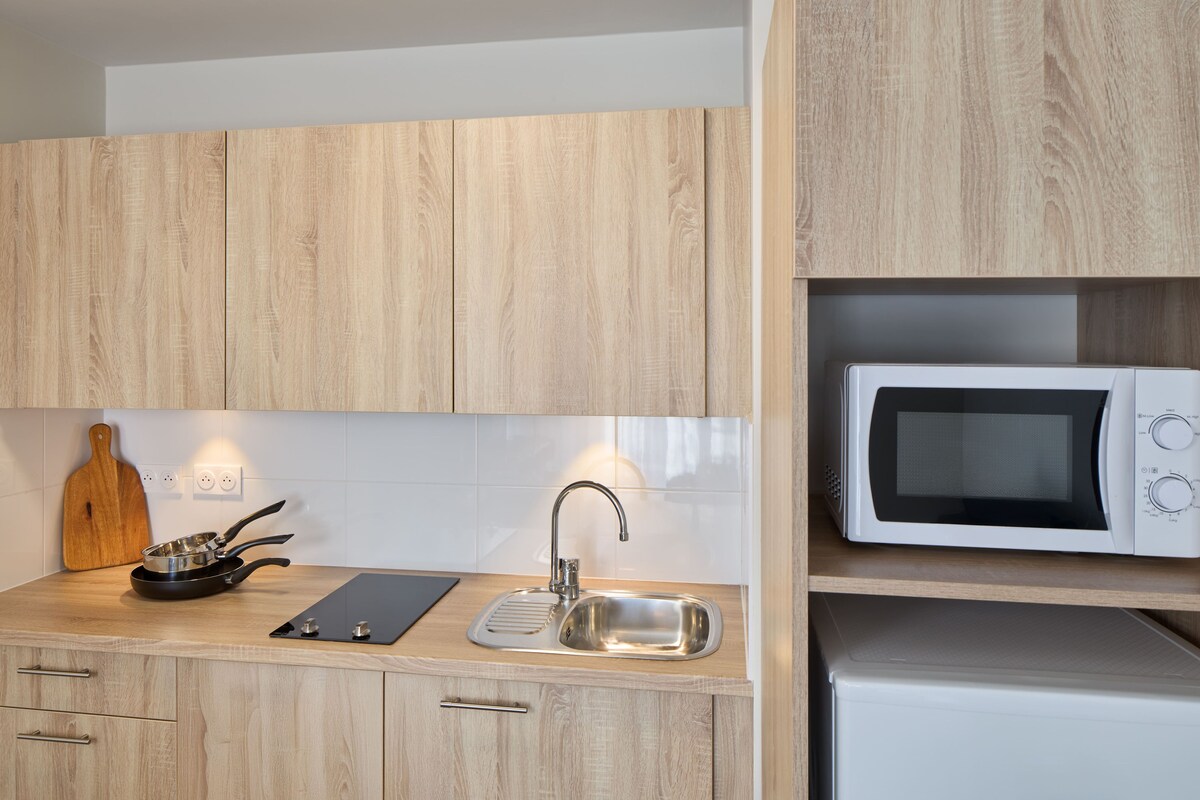 Une cuisine avec des meubles en bois, un évier en acier inoxydable, un four à micro-ondes et une planche à découper.