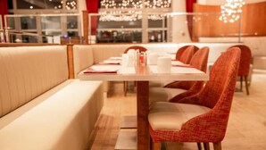 A restaurant with a long table, cushioned booths, and red upholstered chairs. - Quality Aparthotel Nancy Centre (Nancy)