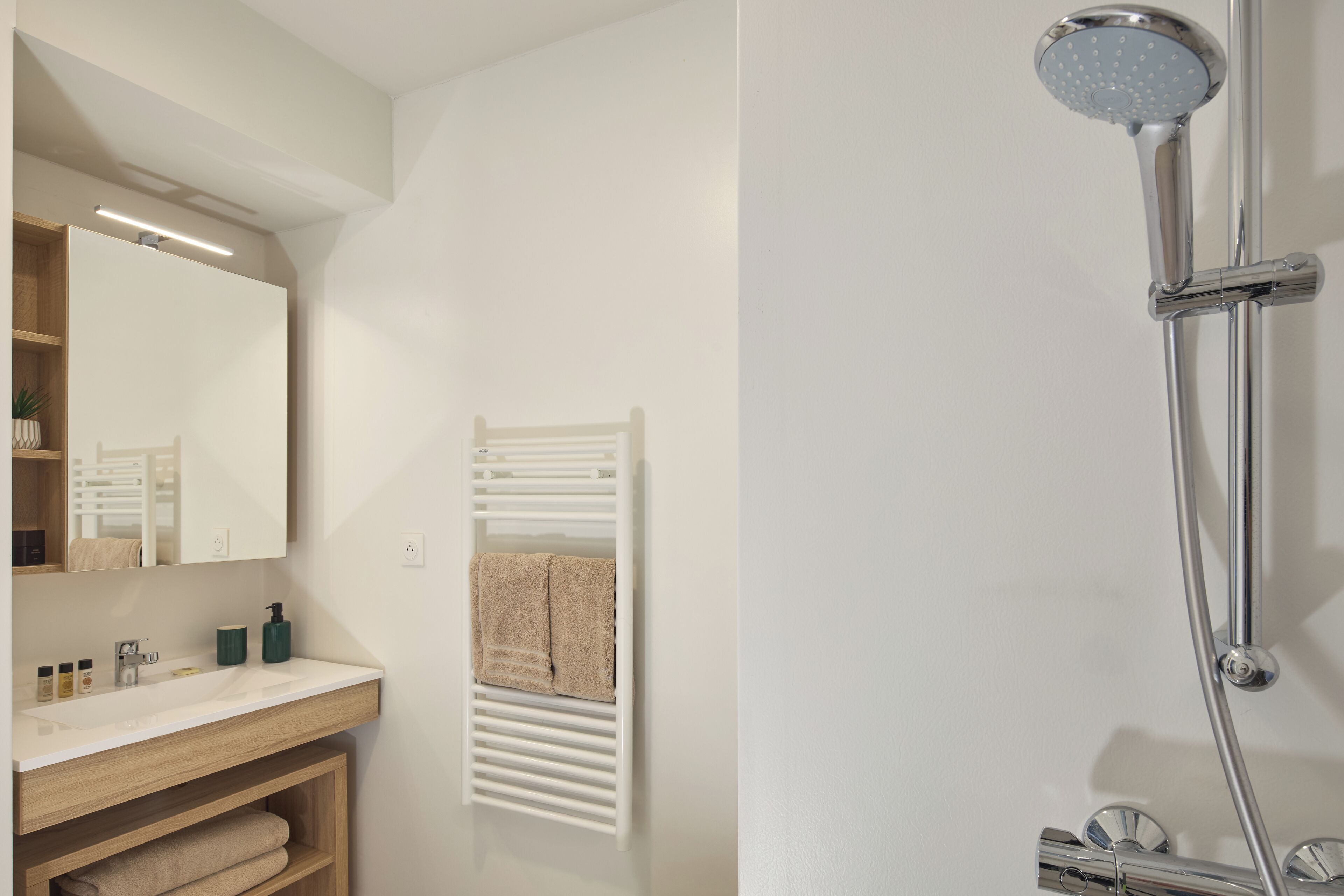 A bathroom with a white sink, mirror, and shower.