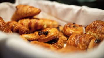 A basket of assorted pastries, including croissants and muffins, arranged on a white surface.