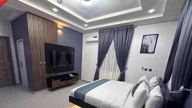Une chambre à coucher moderne, équipée d’un lit, d’une télévision et de rangements intégrés.