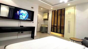 Ein modernes Hotelzimmer mit einem großen Bett, einem an der Wand befestigten Fernseher, einem Kleiderschrank und einem kleinen Tisch.