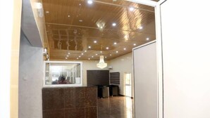 Un hall d’entrée spacieux, doté d’un haut plafond, d’un grand miroir et d’un lustre.