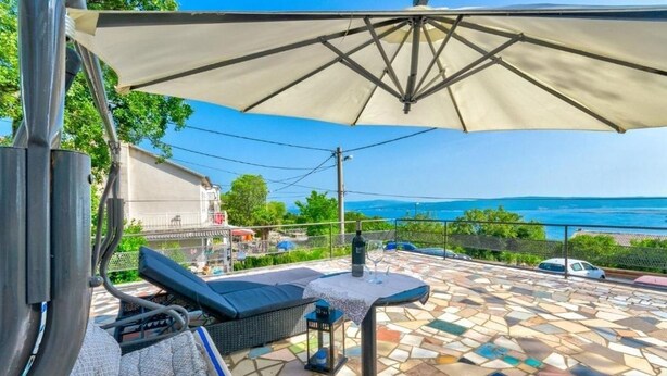 Une terrasse dotée d’un sol en mosaïque, de sièges extérieurs et offrant une vue sur la mer.