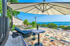 A patio with a mosaic floor, outdoor seating, and a view of the sea.