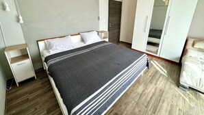 Une chambre à coucher comprenant un lit, des tables de chevet, une armoire et un lustre.