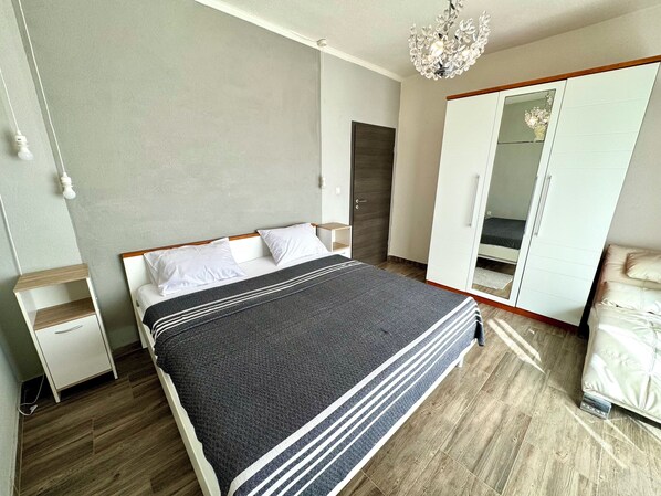 A bedroom with a bed, bedside tables, a wardrobe, and a chandelier.