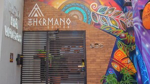 A hotel entrance with a modern design, featuring a metal gate and a colorful mural on the wall. - Che Hermano Suítes (Foz do Iguaçu)