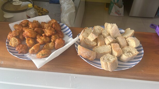 Two plates of food, one with fried items and the other with bread, on a kitchen counter.