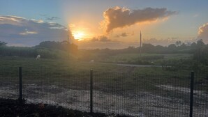 A fenced field with a sunset in the background.