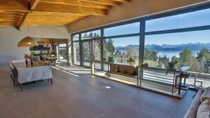A spacious living area with large windows, a dining table, and a sofa. - House of Light Bariloche (San Carlos de Bariloche)