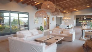 A modern living room with white sofas, wooden coffee tables, and wicker pendant lights. - House of Light Bariloche (San Carlos de Bariloche)