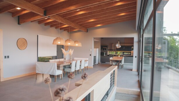 A modern kitchen with a large island, a dining area with a long table and chairs, and a staircase leading to an upper level. - House of Light Bariloche (San Carlos de Bariloche)