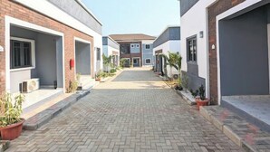 A residential building with a central courtyard, featuring a paved walkway and potted plants. - Urban Edge Comfort Apartment (Lokoja)
