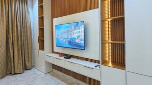 A modern living room with a flat-screen TV mounted on a white entertainment unit, wooden slats on the walls, and a marble-patterned floor. - Urban Edge Comfort Apartment (Lokoja)