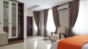 A hotel room with a bed, a chair, a wardrobe, and curtains. - Urban Edge Comfort Apartment (Lokoja)