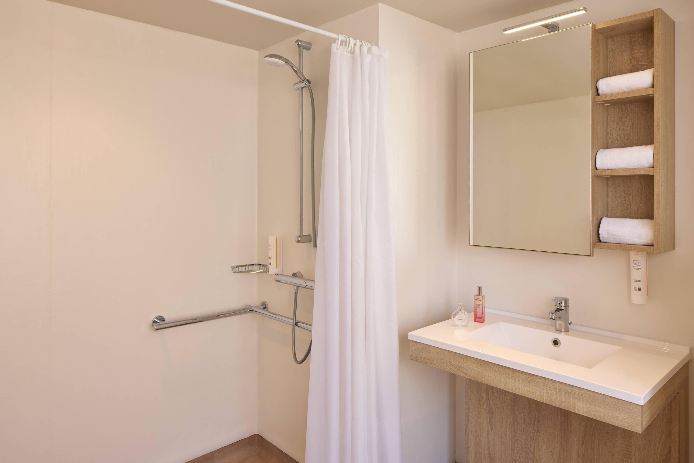 A modern bathroom with a shower, a sink, and a mirror.