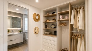 A walk-in closet with hanging space, shelves, and drawers, featuring hats, baskets, and a clock. - Esperanza Grand Apartments II • Marbella Centro (Marbella)