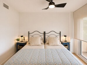 Una camera da letto con un letto, due comodini, una ventola a soffitto e una finestra.