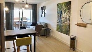 A modern living room with a dining area, a grey sofa, a coffee table, and a large abstract painting on the wall. - Esperanza Grand Apartments I • Marbella Center (Marbella)