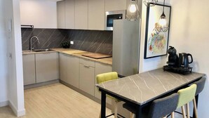 A modern kitchen with grey cabinets, a marble backsplash, and a dining area with a marble table and chairs. - Esperanza Grand Apartments I • Marbella Center (Marbella)