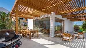 An outdoor patio with a wooden pergola, a dining area with wooden furniture, and a barbecue grill. - Villa 1 (Soline)