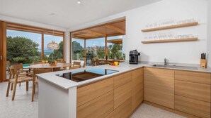 A modern kitchen with a central island, wooden cabinetry, and a view of the outdoors. - Villa 1 (Soline)
