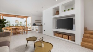 A modern living room with a flat-screen TV, wooden furniture, and a dining area with natural light. - Villa 1 (Soline)